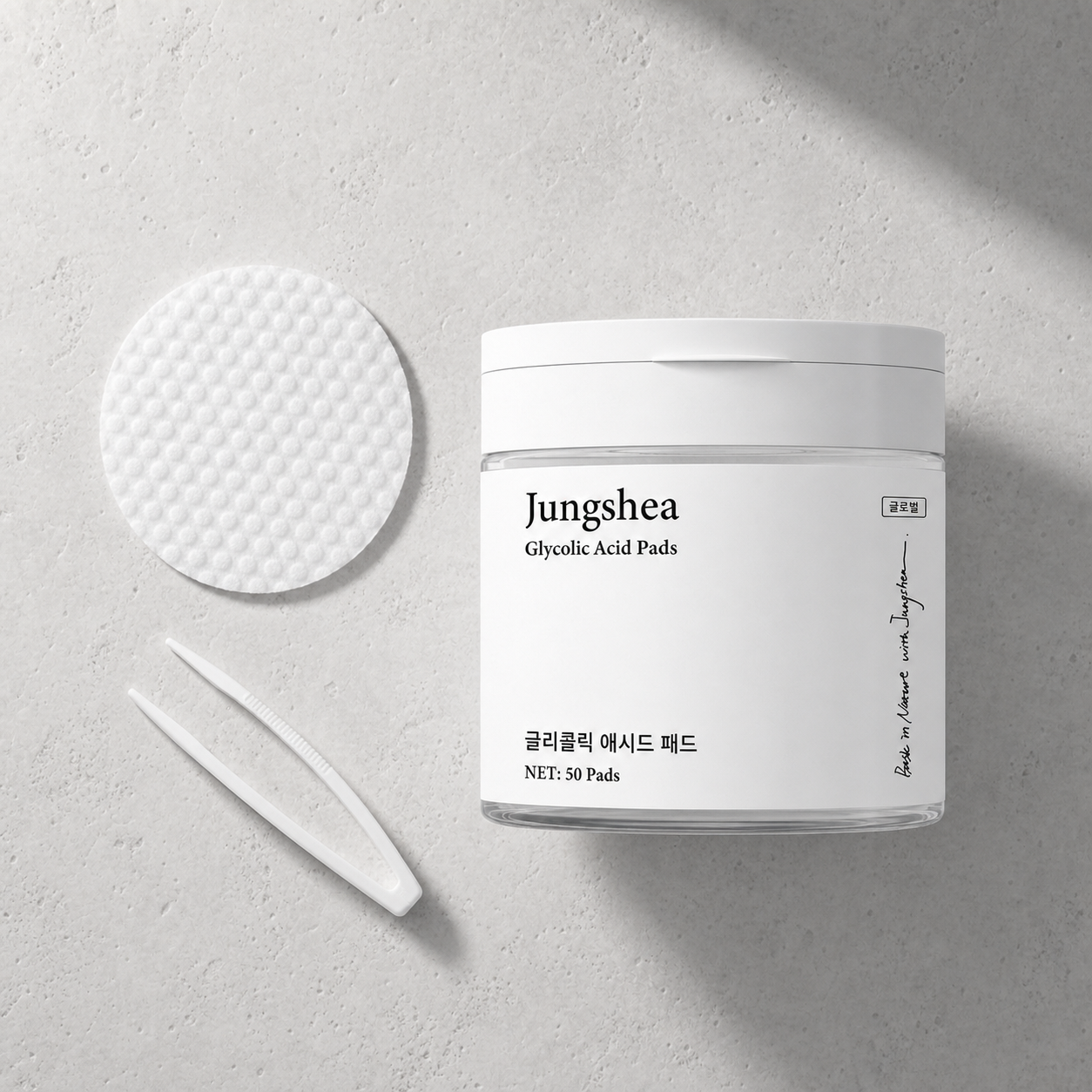 Jungshea exfoliating pads jar, textured pad, and white tweezers in a flat lay