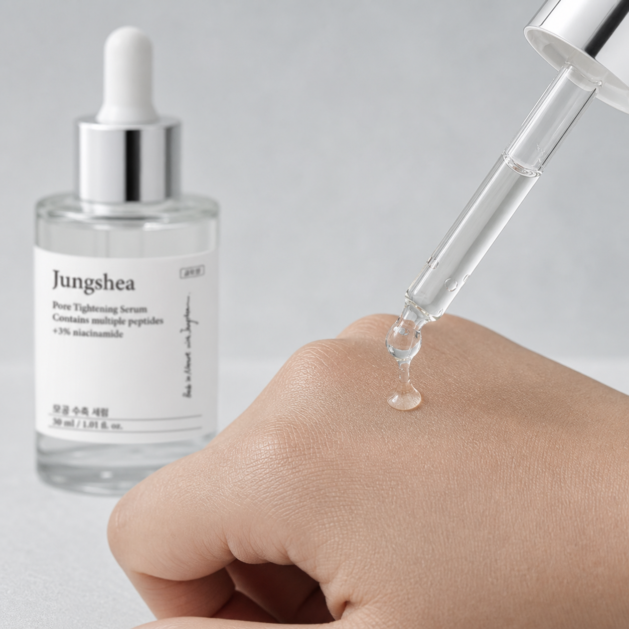 Clear serum dispensed from a glass dropper onto the back of a hand